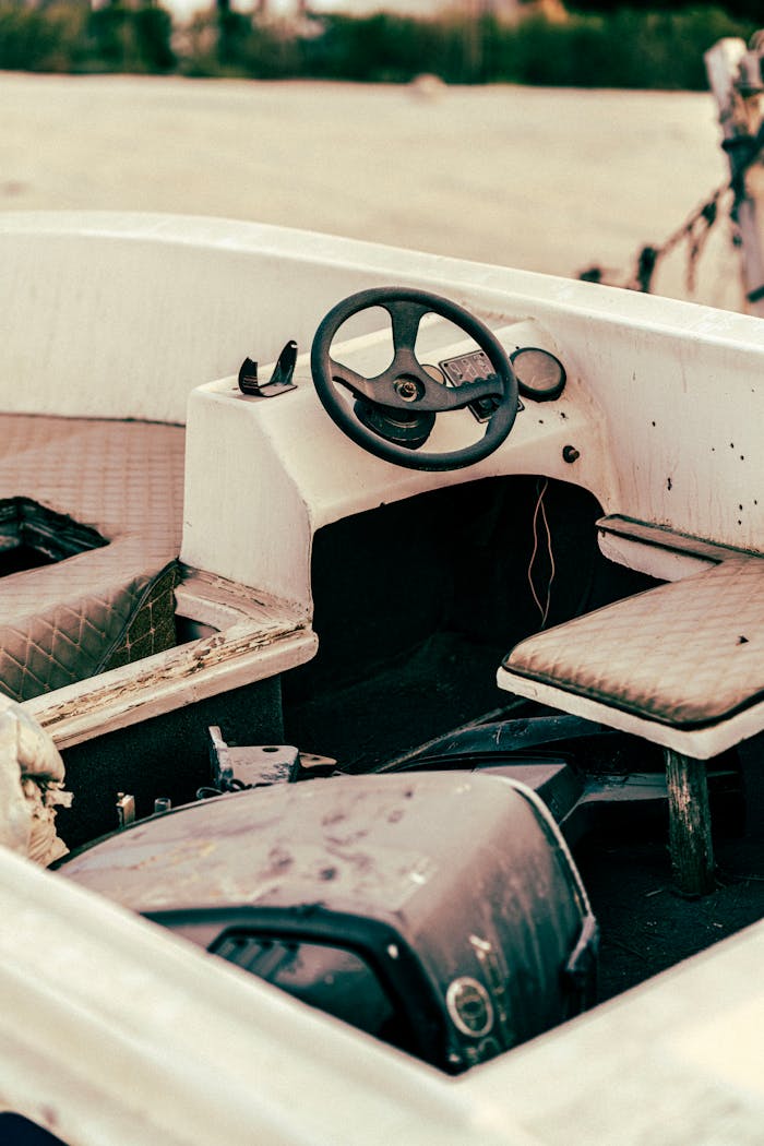 services-02 Close-up of a weathered motorboat interior showing the steering wheel and seating area.
