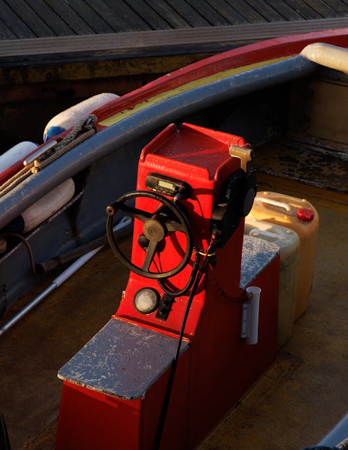 services-03 Close-up of a rustic rowboat's red steering console, showcasing maritime textures.