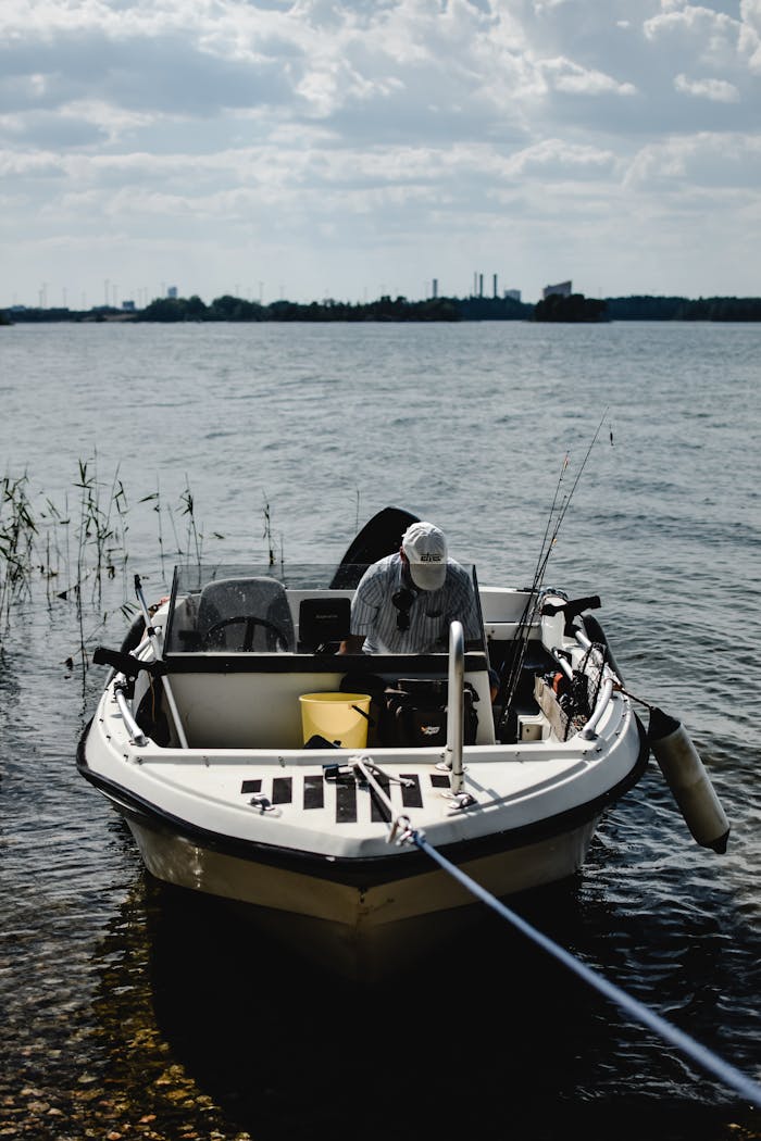 why-choose-us A person fishing alone on a serene lake in Finland with a cloudy sky overhead.